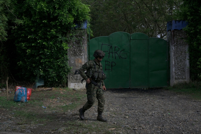 Soldado colombiano pasa junto a puerta de garaje metálica con la inscripción “FARC-EP”,  (Fuerzas Armadas Revolucionarias de Colombia) Ejército del Pueblo, en Jamundi, departamento del Valle del Cauca, Colombia, el 27 de abril de 2026.
