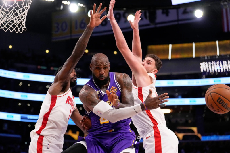 LeBron James, el delantero de los Lakers, evade la defensa de dos jugadores y da un pase a un compañero en el partido contra Houston.