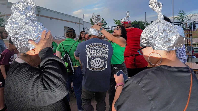 Asistentes juegan con sombreros de papel de plata en el Edinburg UFO Festival, el 5 de abril de 2024 en Edinburg, Texas
