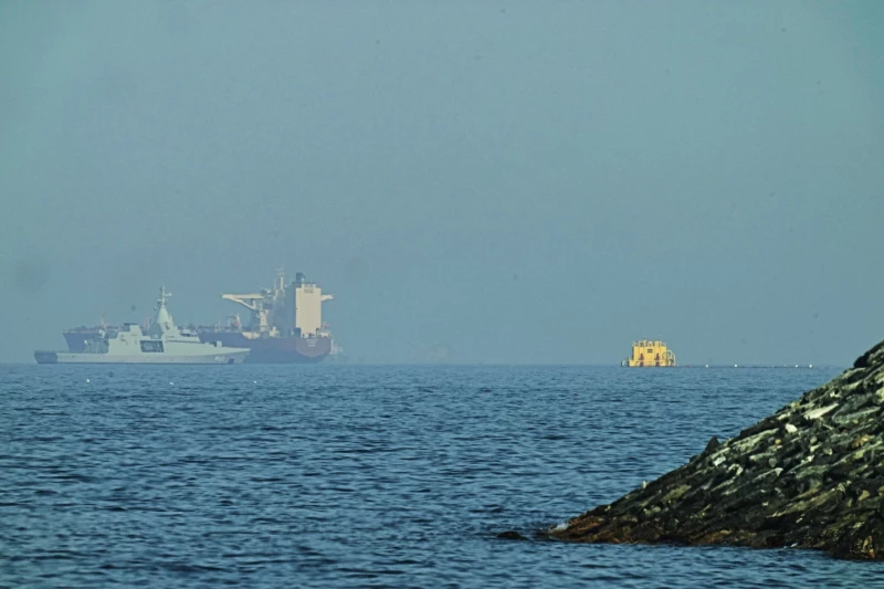 Una patrullera emiratí, izquierda, navega cerca de un petrolero fondeado en el golfo de Omán, cerca del estrecho de Ormuz, vistos desde una carretera costera cerca de Khor Fakkan, Emiratos Árabes unidos, el 1 de mayo de 2026.