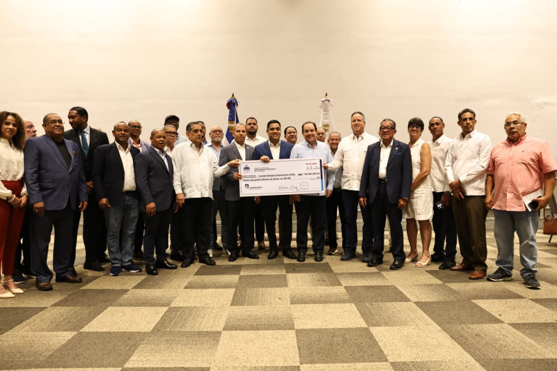 El ministro de Deportes, Kelvin Cruz, acompañado del vicemintro Administrativo, Franklin de la Mota, entrega una réplica del cheque por valor de 150 milllones de pesos a Garibaldy Bautista, Luis Chanlatte, José Mera e Irina Pérez, principales directivos del COD. Observan los dirigentes federados Alexis García, Gilberto García, Gilberto Soriano y Nelson Javier, entre otros.