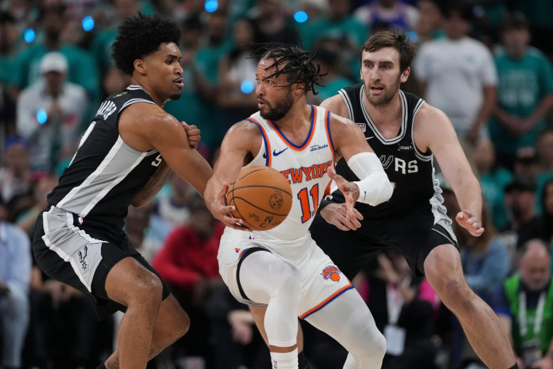 El armador Jalen Brunson mantiene el control del balón mientras era defendido muy de cerca por dos jugadores de las Espuelas.