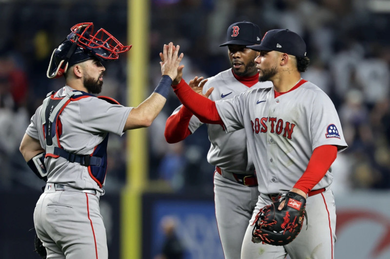 Willson Contreras saluda a Connor Wong y Aroldis Chapman tras ganar el partido ante Yanquis.