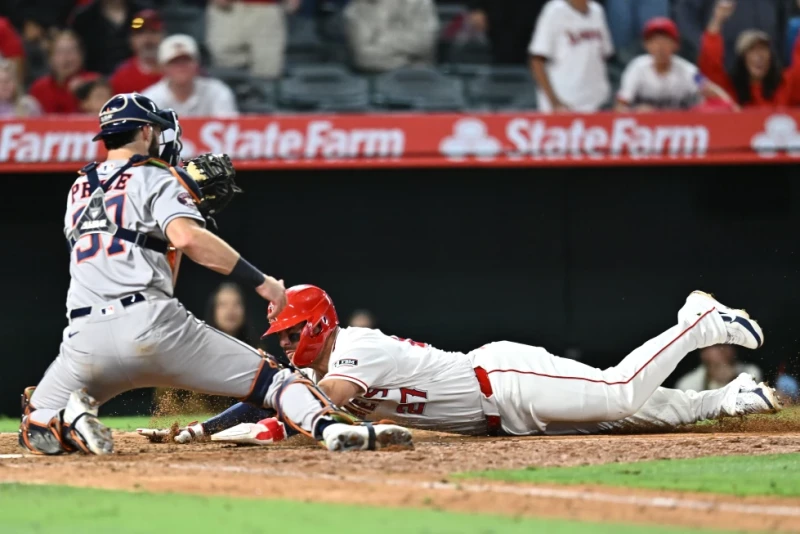 Mike Trout, de los Angelinos, se barre en el plato pero es puesto fuera en la décima entrada del juego de Grandes Ligas, el 8 de junio de 2026, en Anaheim, California.