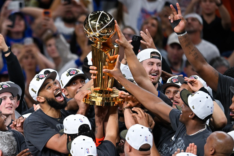 Karl Towns celebra junto a sus compañeros tras sostener el trofeo de campeón de la NBA.