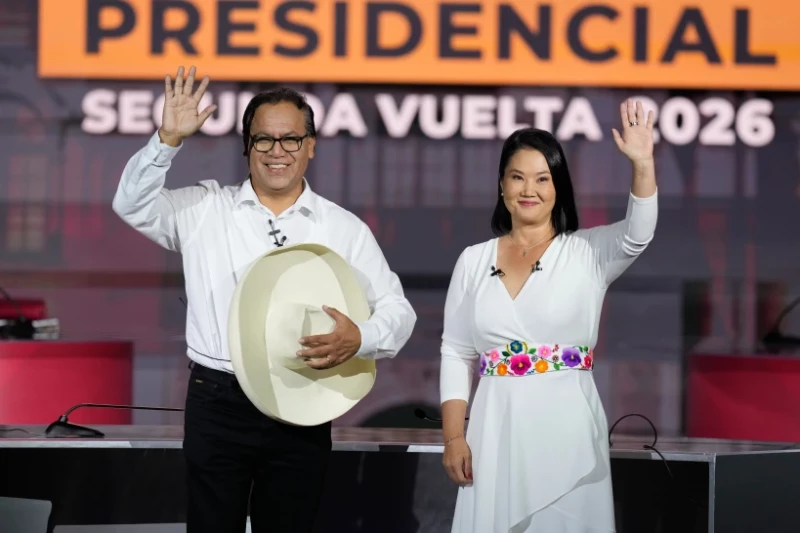 La candidata presidencial Keiko Fujimori, del partido Fuerza Popular, y su rival Roberto Sánchez, del partido Juntos por el Perú, saludan con la mano durante un debate presidencial.