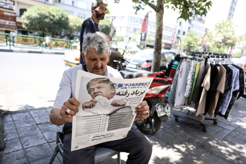 Un hombre lee un ejemplar del diario iraní Hamshahri, que lleva la imagen del presidente de Estados Unidos y un titular que reza "Lo que el viento se llevó", en un quiosco de Teherán el 18 de junio de 2026.