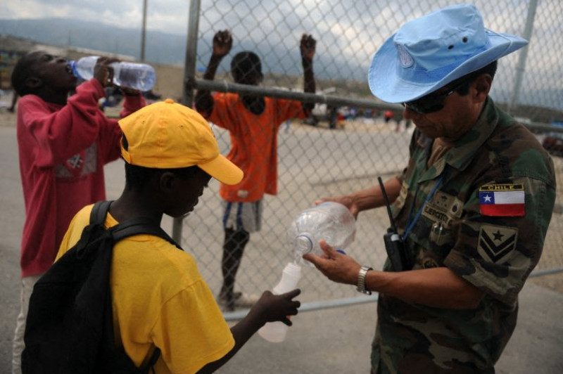 Un casco azul de la ONU reparte agua a niños haitianos en una base militar de la ONU en Puerto Príncipe el 27 de febrero de 2010.