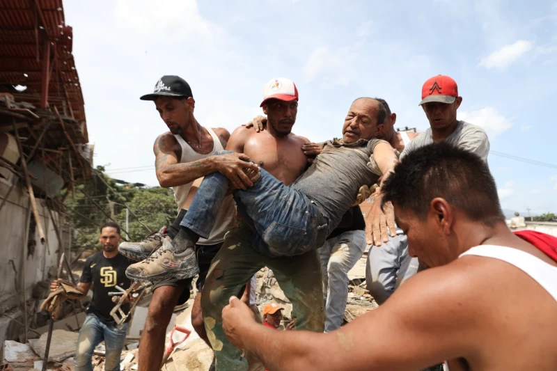 Varios vecinos trasladan a un hombre rescatado de entre los escombros de un edificio derrumbado, un día después de los sismos ocurridos en La Guaira, Venezuela, el jueves, 25 de junio de 2026.
