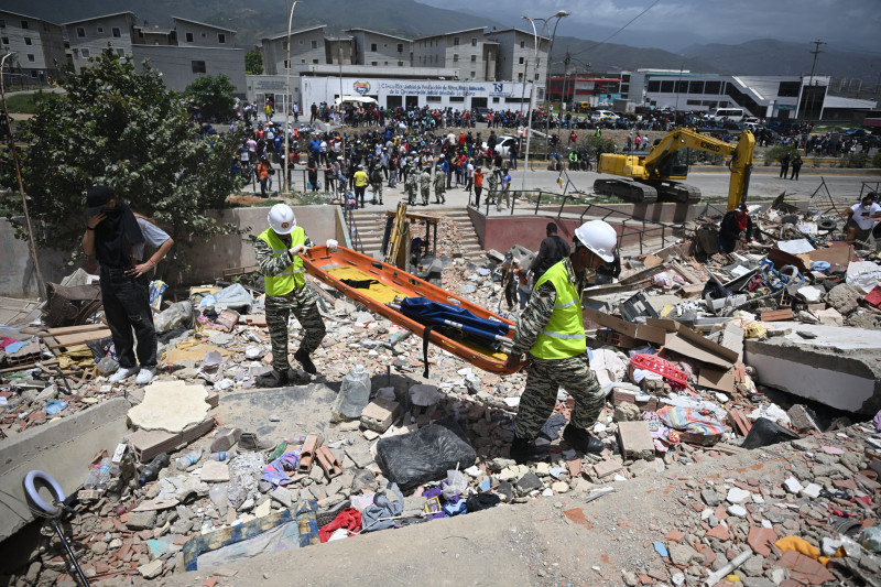 Miembros de la Policía Nacional Bolivariana transportan una camilla entre los escombros de los edificios dañados en Catia La Mar, La Guaira, Venezuela, el 26 de junio de 2026, tras los mortíferos terremotos