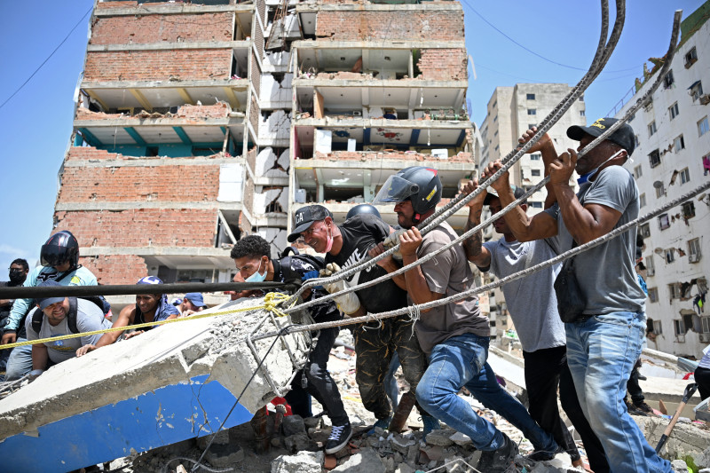 Voluntarios intentan remover escombros mientras buscan cuerpos entre los restos de edificios derrumbados en Catia La Mar, La Guaira,