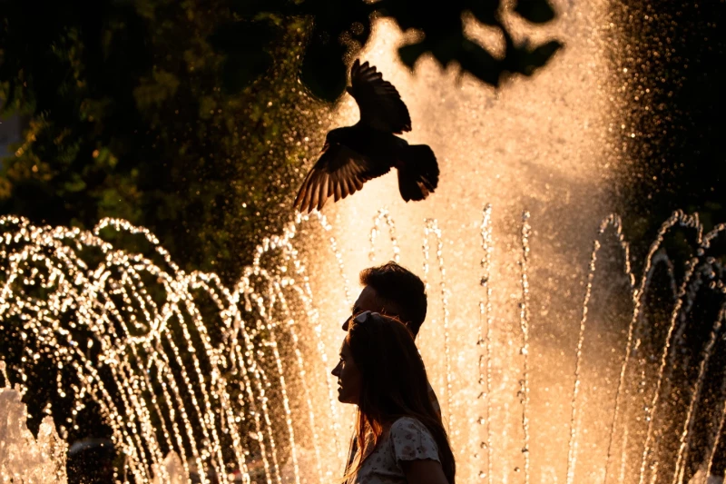 Una pareja pasa por una fuente pública en un día caluroso, en el que la Agencia Nacional de Meteorología emitió una alerta roja por calor extremo en partes del país, en Bucarest, Rumanía, el sábado 27 de junio de 2026.