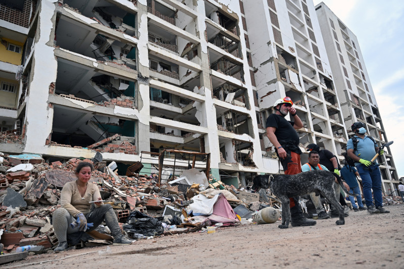 Un rescatista español con un perro de búsqueda descansa junto a rescatistas voluntarios frente a un edificio parcialmente derrumbado en Caraballeda, estado de La Guaira, Venezuela, el 3 de julio de 2026.