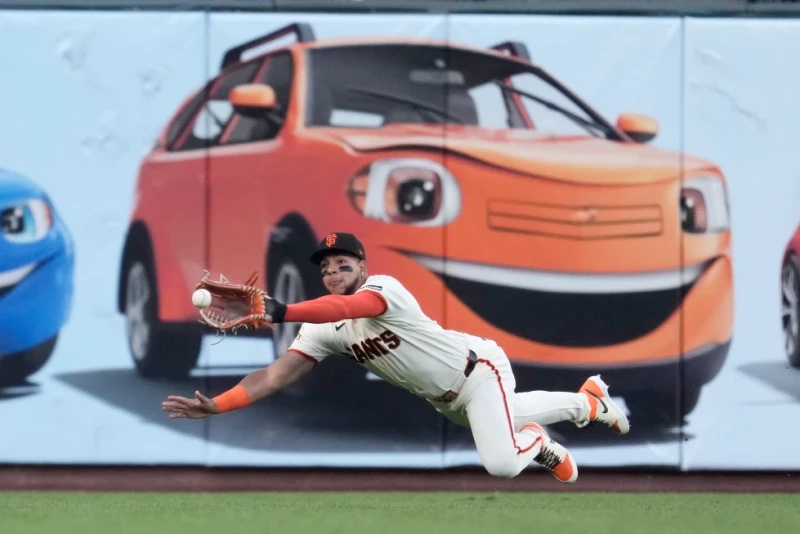 El jardinero de los Gigantes, Victor Bericoto, se zambulle para atrapar un elevado bateado por Cole Carrigg, de los Rockies, el 9 de julio de 2026, en San Francisco.