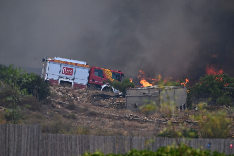 Una fotografía tomada el 10 de julio de 2026 muestra un camión de bomberos en una carretera junto a las llamas, cerca de una caseta de jardín, en la zona de un incendio forestal que causó 11 muertos cerca de Bedar, en el municipio de Los Gallardos (provincia de Almería).