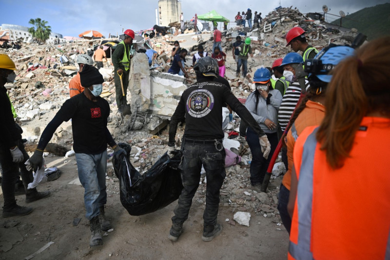 Voluntarios de los equipos de rescate transportan una bolsa para cadáveres sobre los escombros de un edificio derrumbado en Caraballeda, Venezuela, el 17 de julio de 2026, tras los terremotos del 24 de junio.