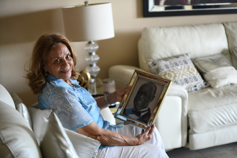 Josefina de Ventura en su casa, el jueves 23 de julio de 2026. Ella posa junto a un retrato especial de Johnny Ventura.