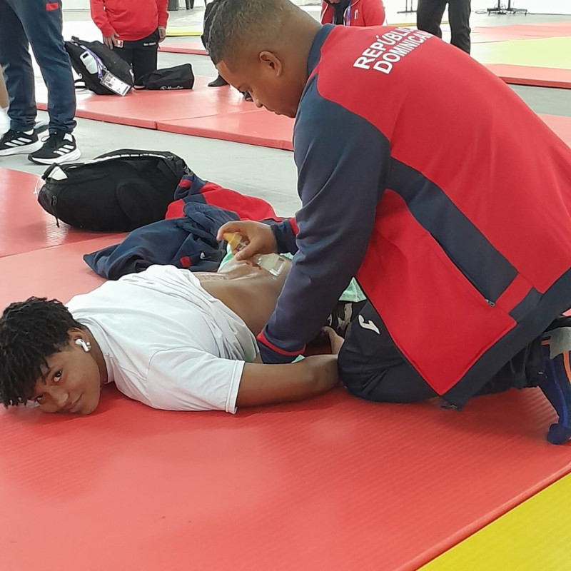 Dalver De los Santos masajea en el tátami a una de las atletas dominicanas que compitieron en la justa regional.