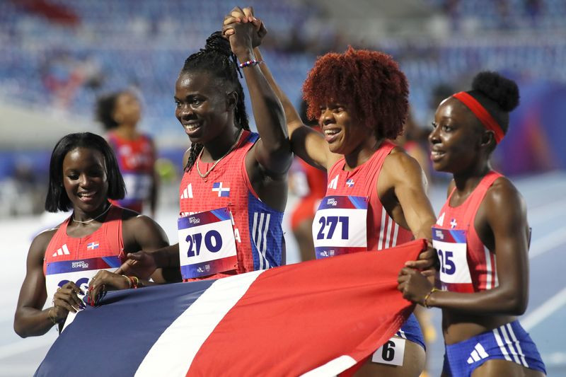 Liranyi Alonso, Fiordaliza Cofil, Patricia Sine y Estrella De Aza, campeonas del relevo 4x100, sostienen la bandera dominicana tras alcanzar la presea dorada de Santo Domingo 2026.