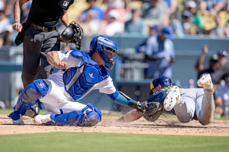 Jake Bauers, de los Cerveceros, se desliza en el plato mientras Ben Rortvert, de los Dodgers, trata de ponerlo out, el 16 de agosto de 2026, en Los Angeles.