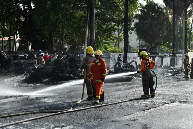Bomberos del Distrito Nacional trabajan en limpiar el área donde un tanquero cargado de gasoil explotó, dejando a dos personas fallecidas.