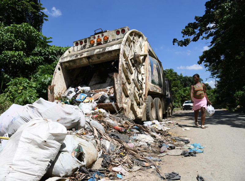Momento en que un camión colector de basura realiza una descarga de desperdicios en un lateral de una vía del sector La Isabela.