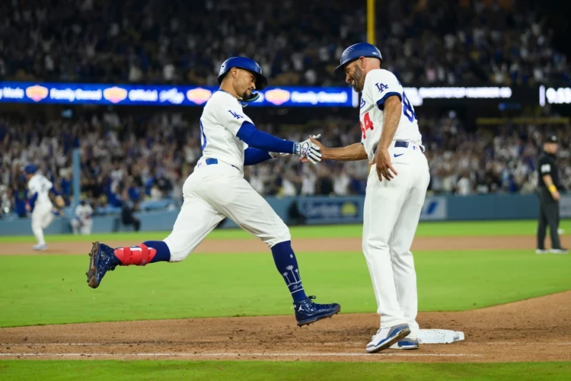 Mookie Betts, de los Dodgers, celebra su cuadrangular con el coach de primera base, Chris Woodward, durante la octava entrada contra los Nacionales.