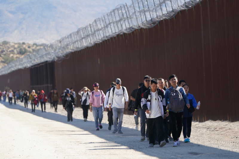 ARCHIVO - Un grupo de personas, incluidos muchos de China, camina junto al muro tras cruzar la frontera con México para pedir asilo, el 24 de octubre de 2023, cerca de Jacumba, California. (AP Foto/Gregory Bull, Archivo)
