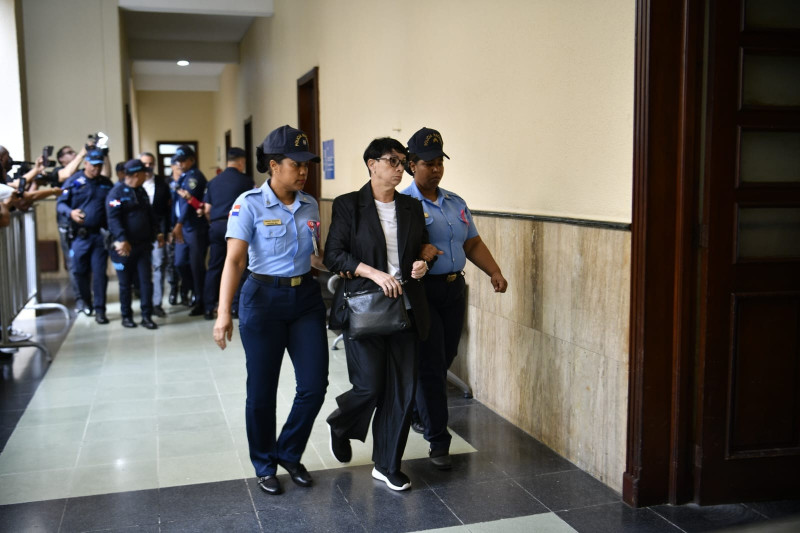 Maribel Espaillat,  una de las propietarias, junto con su hermano Antonio Espaillat, del centro nocturno Jet Set, siendo conducida a los tribunales por agentes de seguridad durante el proceso judicial.