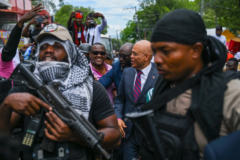 El expresidente de Haití, Michel Martelly (centro-derecha), aparece rodeado de personal de seguridad y simpatizantes a su llegada a una oficina electoral para inscribirse como candidato presidencial en Puerto Príncipe, Haití, el 23 de octubre de 2026.