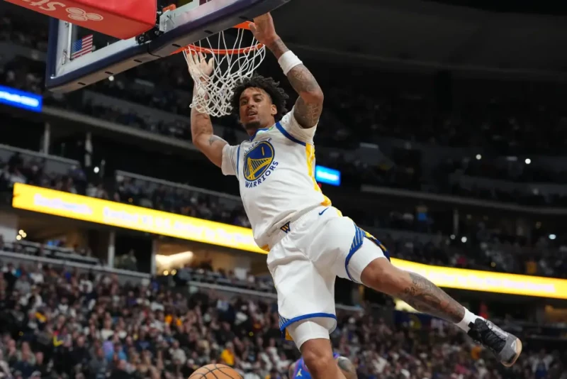Yaxel Lendeborg, de los Warriors, se cuelga del aro después de clavar el balón en el juego de la NBA en contra de los Nuggets, el 6 de octubre de 2026, en Denver.