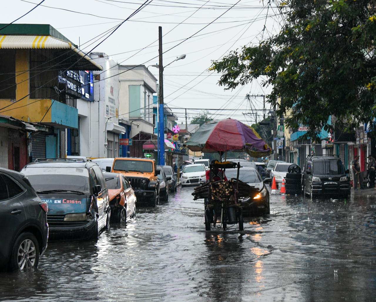 Vehículos se desplazan por una calle inundada durante la Tormenta Melissa