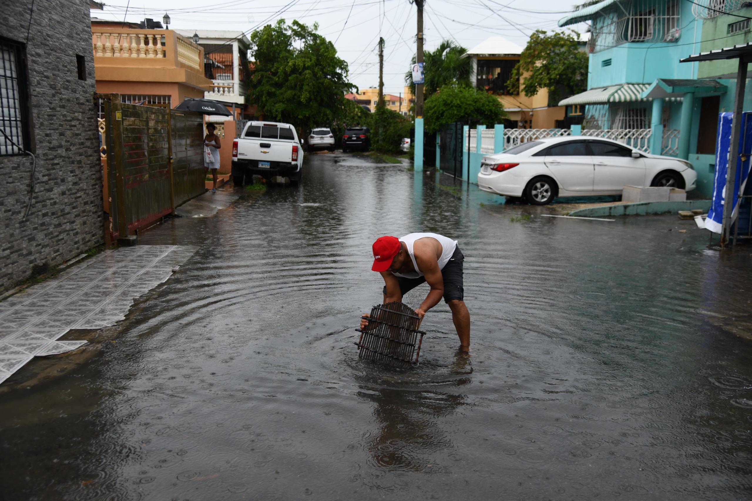 Un hombre saca de entre el agua pertenencias personales arrastradas por los aguaceros.