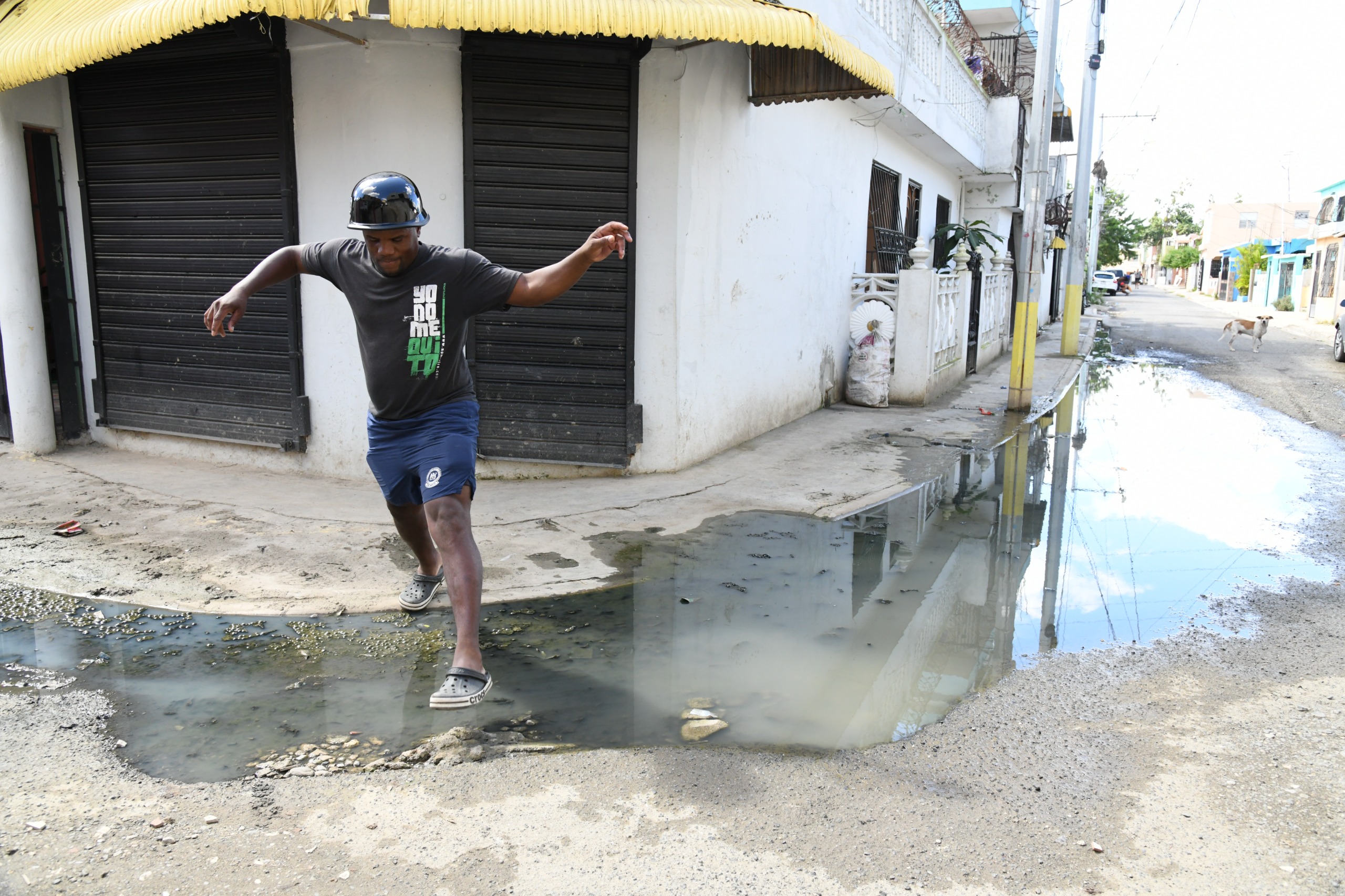 Vecino del sector El Almirante Caña mientras cruzando cúmulo de agua contaminada.