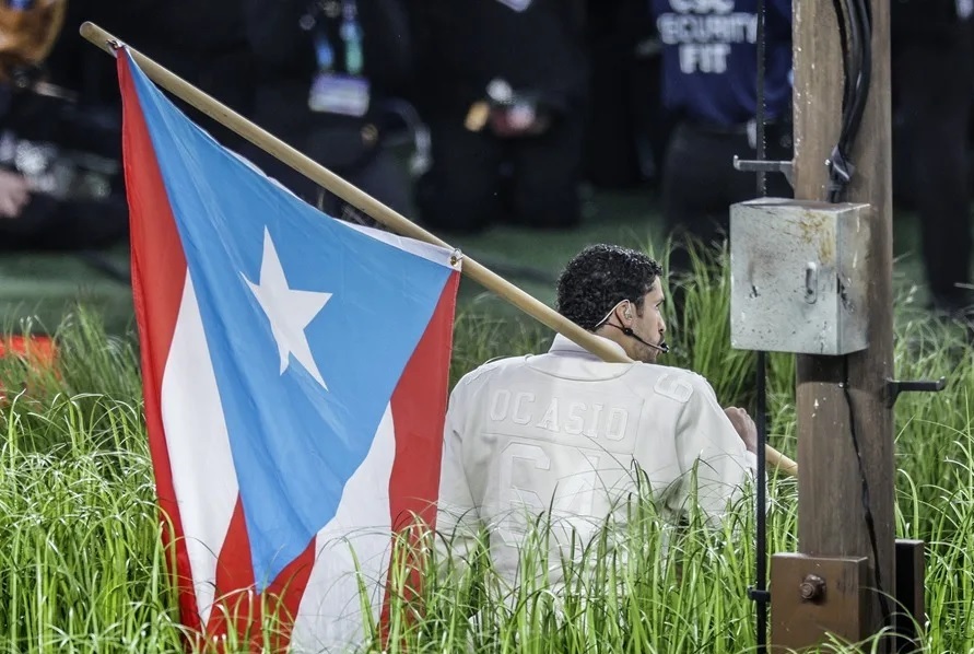 Fotografía del cantante Bad Bunny sosteniendo una bandera de Puerto Rico durante su presentación en el medio tiempo del Super Bowl LX.